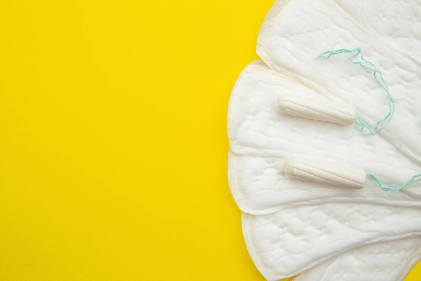Tampones y almohadillas menstruales sobre un fondo amarillo. Ciclo de menstruación. Concepto de higiene y protección
 - Foto, Imagen