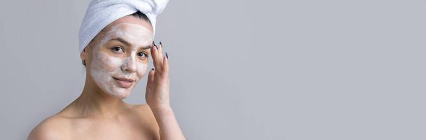 Portrait de beauté de femme en serviette blanche sur la tête applique crème sur le visage. Soin nettoyant éco cosmétique bio spa relax concept. - Photo, image