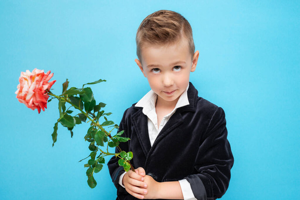 Portrait of a little preschooler in a suit with a rose in his hands - Foto, Imagem