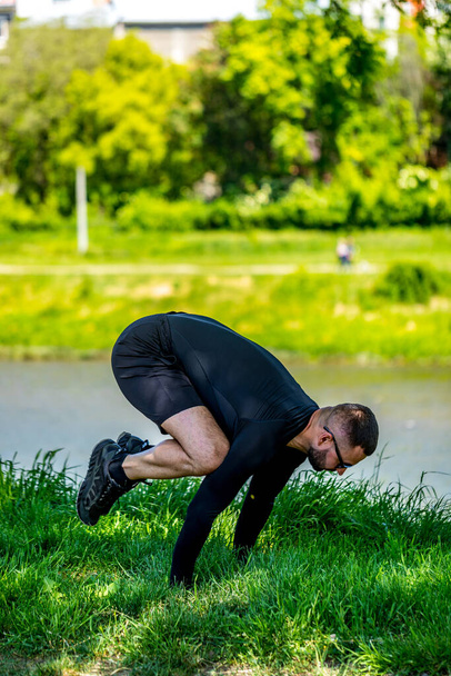 Гарний, м'язистий, сильний чоловік тренується біля озера, роблячи йогу. Концентрований дорослий спортсмен робить підштовхуючі вправи
. - Фото, зображення