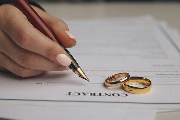 Hands of wife, husband signing decree of divorce, dissolution, canceling marriage, legal separation documents, filing divorce papers or premarital agreement prepared by lawyer. Wedding ring - Photo, Image