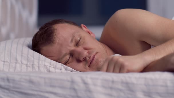 A man can't sleep because of the noise, covers his ears with a pillow - Footage, Video