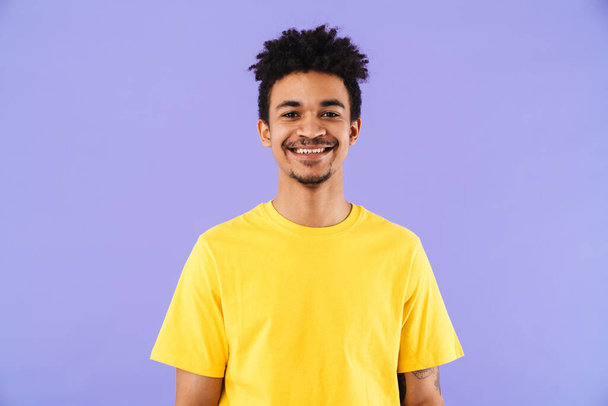 Photo of funny african american man smiling and looking at camera isolated over purple background - Φωτογραφία, εικόνα