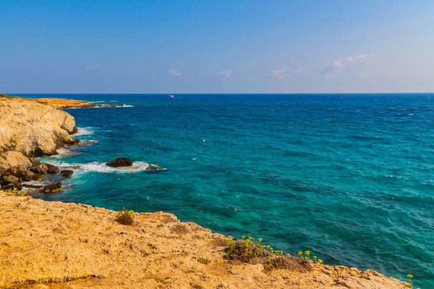 Skalnatý břeh s kamennými útesy a úžasnou modrou vodou v blízkosti jeskyní a mostu milenců, Ayia Napa, Kypr. Středozemní moře. - Fotografie, Obrázek