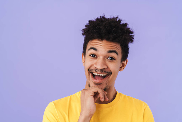 Photo of excited african american man smiling and looking upward isolated over purple background - Fotografie, Obrázek