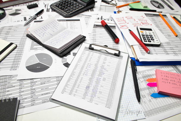 オフィスワーカーのデスクのトップビュー-財務報告書、分析と会計、表とグラフ、予約のためのさまざまなオフィスアイテムと作業 - 写真・画像