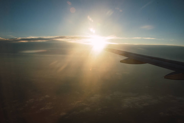 Sunset seen from the window of an airplane, in the golden hour, you can see the clouds and the wing of the airplane, perfect for travel. - Fotó, kép