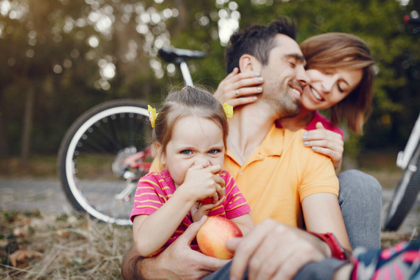 Family with a bicycle in a summer park - Фото, изображение