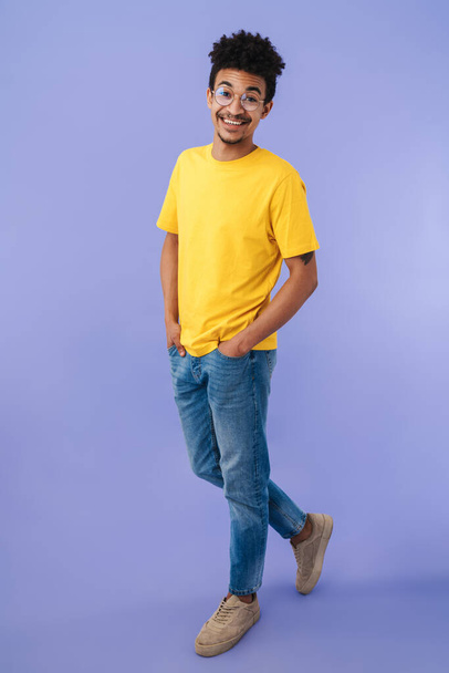 Photo of joyful african american man in eyeglasses smiling and posing at camera isolated over purple background - Foto, afbeelding