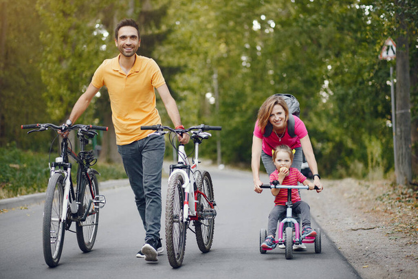 Family with a bicycle in a summer park - Фото, изображение