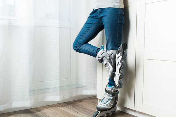 Woman in jeans standing at home near wardrobe in new roller skates - Zdjęcie, obraz