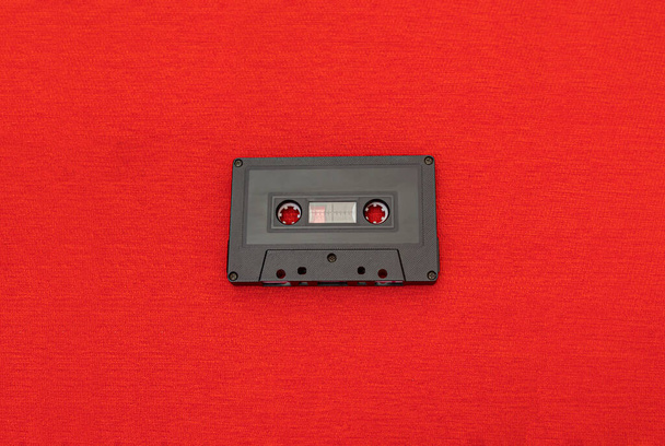 Top Вид старой черной кассеты поверх красной ткани. Концепция моды и ретро музыки
 - Фото, изображение