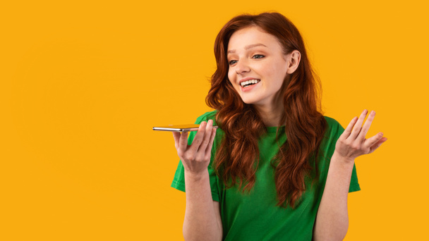 Millennial Girl Using Smartphone Voice Assistant Standing Over Yellow Background - Photo, Image
