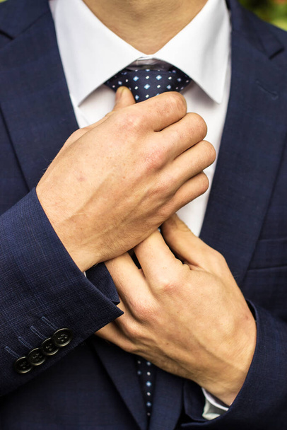 Наречений виправляє краватку своїми руками крупним планом
 - Фото, зображення