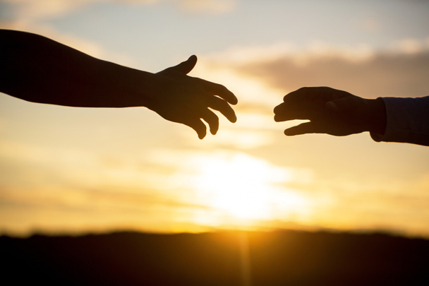 Giving a helping hand. Friendly handshake, friends greeting, teamwork, friendship. Rescue, helping gesture or hands. Outstretched hands, salvation, help silhouette, concept of help - Photo, Image