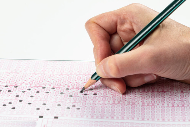 Sınavlara giren öğrencilerin elleri, optik test formunda kalem tutarak sınav kağıtları hazırlıyor ve sınıfta sınav kağıtları hazırlıyor. Eğitim Değerlendirme Kavramı. Yumuşak odak  - Fotoğraf, Görsel