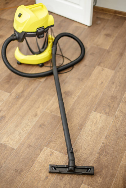 Yellow vacuum cleaner isolated on floor of the parquet in a room - Foto, afbeelding