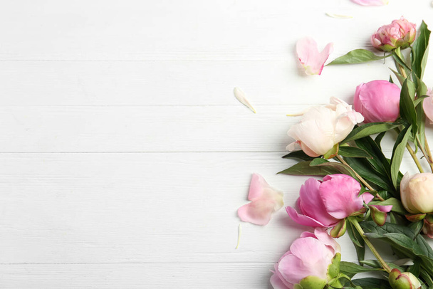 Beautiful peonies on white wooden table, flat lay. Space for text - Foto, afbeelding