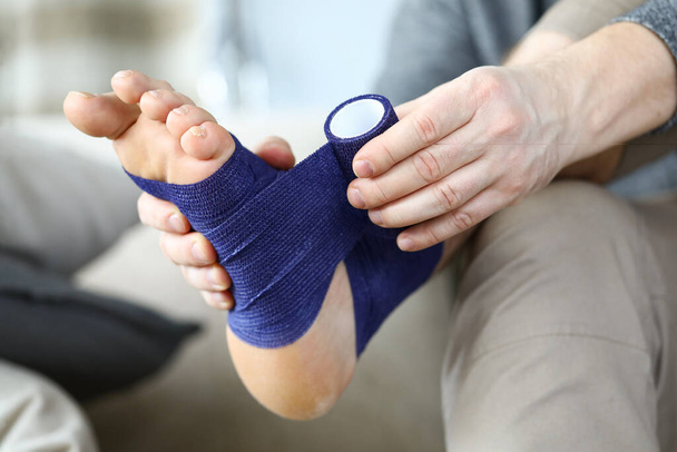 Человек заворачивает ноги эластичной повязкой
 - Фото, изображение