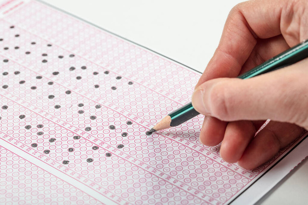 Iskolások kezek vizsgák, írás vizsga holding ceruza optikai formája szabványosított teszt válaszok lap csinál záróvizsga osztályteremben. Oktatás-értékelési koncepció. Lágy fókusz  - Fotó, kép