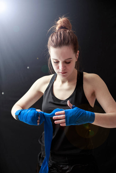 Vonzó fiatal lány bokszoló koncentrált húzza a kötést a kezét - Fotó, kép