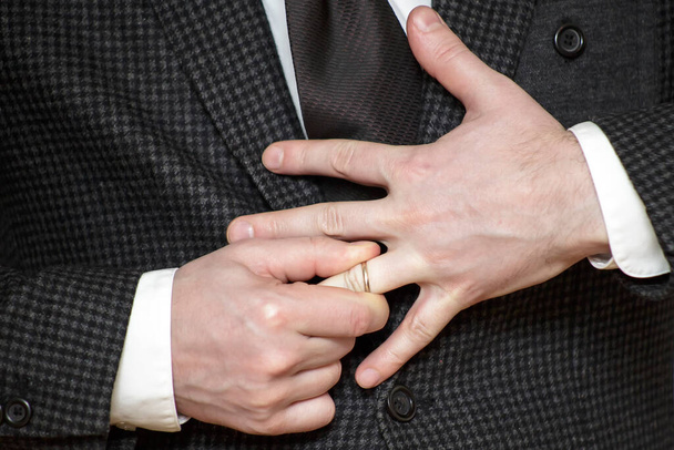 Mann in Jacke kämpft darum, Ehering aus Finger zu entfernen - Foto, Bild