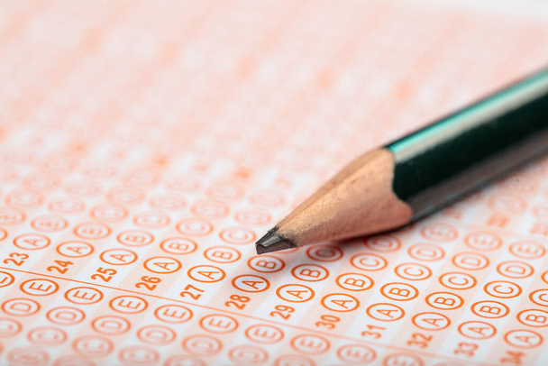 Uczniowie podchodzą do egzaminów, piszą egzamin trzymając ołówek na optycznej formie znormalizowanego testu z arkuszem odpowiedzi wykonując egzamin końcowy w klasie. Ocena edukacji Koncepcja. Miękkie skupienie  - Zdjęcie, obraz