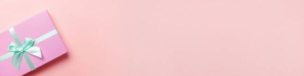 Weihnachten Silvester Geburtstag valentine Feier präsentieren romantisches Konzept. Einfach minimalistisches Design rosa Geschenkbox isoliert auf rosa pastellfarbenem Hintergrund. Flache Lageansicht Kopierraum-Banner - Foto, Bild