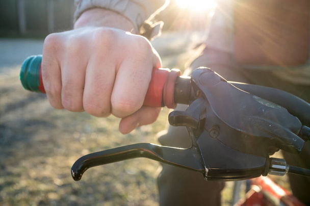 Mužská ruka na kormidle motorky v paprscích jarního slunce. Detailní záběr. - Fotografie, Obrázek
