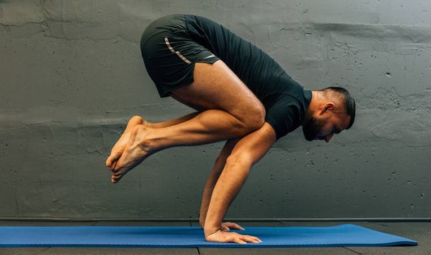 Sportos fiatalember edz, kézen állva jógázik. Stúdió forgatott városi fitness tornaterem szürke háttérrel másolás tér. - Fotó, kép