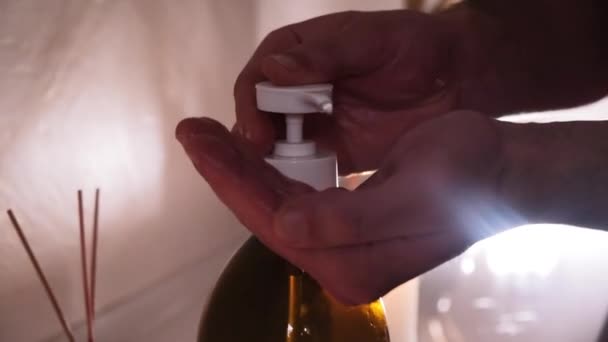 Hands of masseur with body oil before massage in salon romantic light - Felvétel, videó