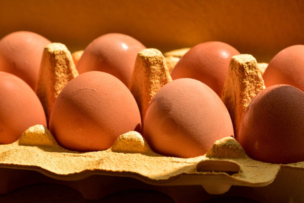 Ovos de galinha em papel kraft amarelo. Ovos de galinha. Ovos em uma caixa de papelão de manhã
 - Foto, Imagem