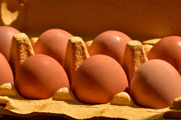 Huevos de pollo en papel kraft amarillo. Huevos de pollo. Huevos en una caja de cartón por la mañana
 - Foto, imagen
