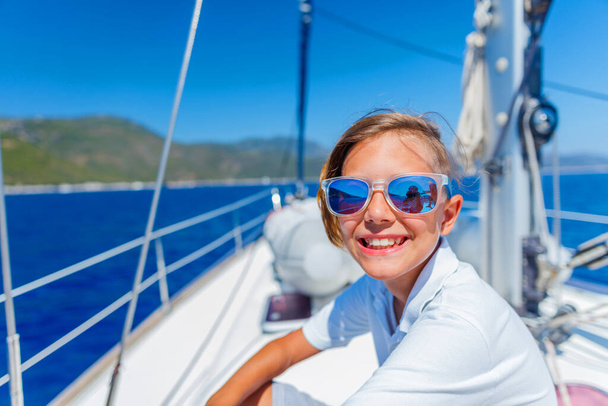 Little boy on board of sailing yacht on summer cruise. Travel adventure, yachting with child on family vacation. - 写真・画像