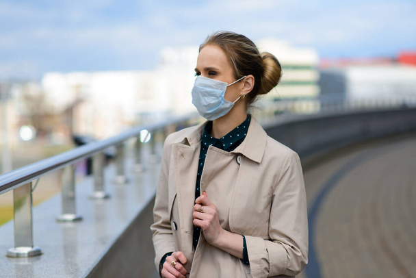 Une jeune femme d'affaires portant un masque de santé et parlant au téléphone en ville, concept d'isolement et de quarantaine - Photo, image