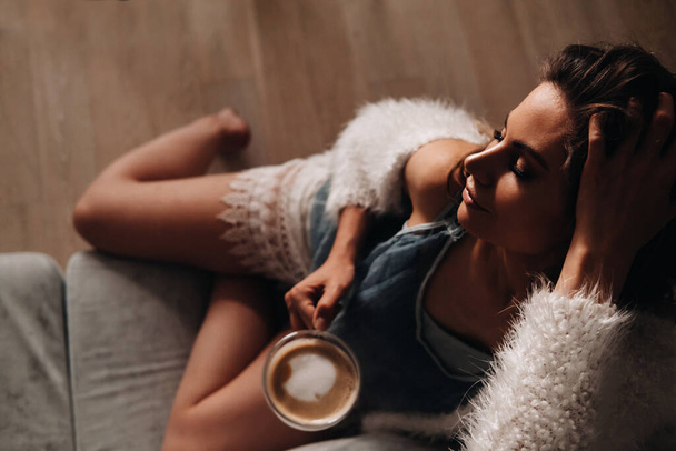 relaxed girl at home drinking coffee.Inner peace.The girl is sitting comfortably on the sofa and drinking coffee. - Foto, afbeelding