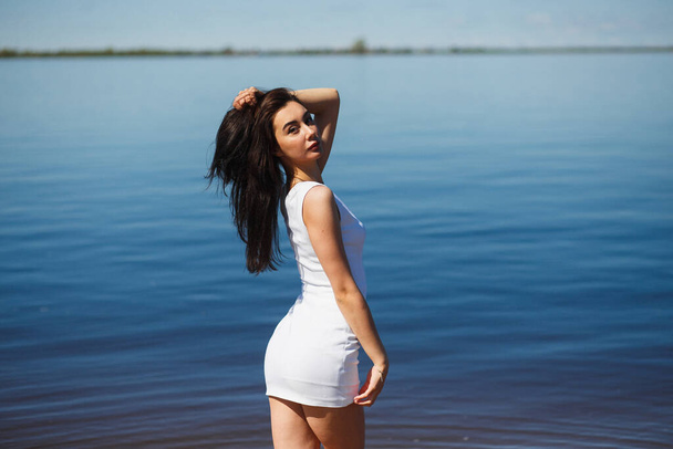 Young sexy lady in the white dress standing in the warm water - 写真・画像