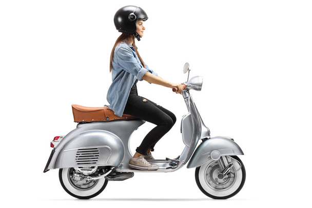 Full length profile shot of a young woman with a helmet riding a vintage scooter isolated on white background - Photo, Image