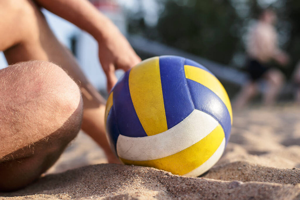 Man resting after playing sitting volleyball on the sand, next to him is a ball, a sunny summer day. - Photo, Image