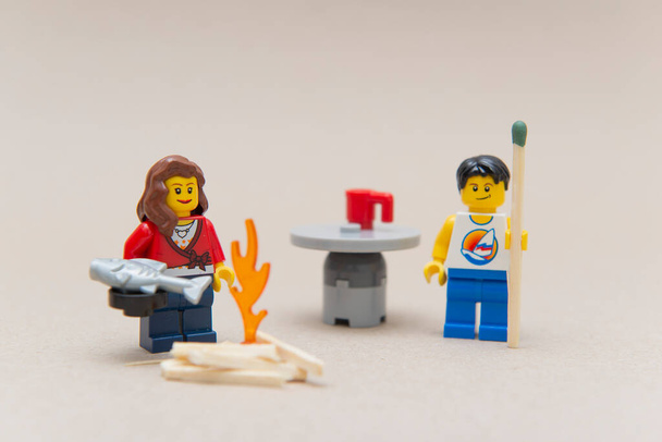 Florianopolis - Brazil, June 14, 2020: Couple minifigures camping and warming up by the fire. Man holding huge matchstick.. Selective focus. Minifigures are manufactured by Lego Group. - Valokuva, kuva