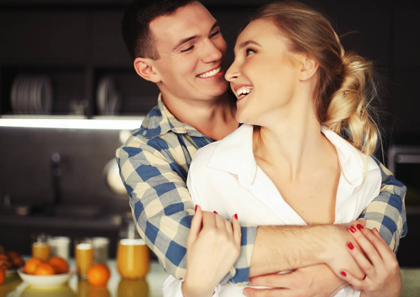 Lovely young couple standing and hugging on a kitchen at home - Fotoğraf, Görsel
