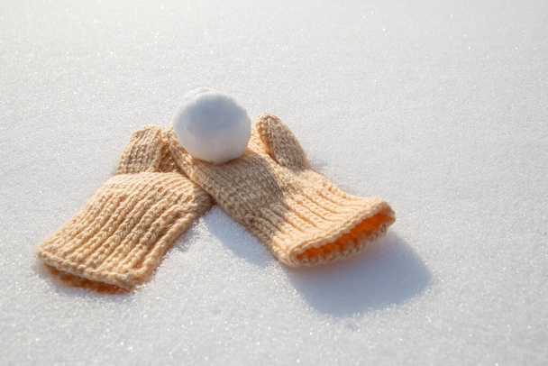 Śnieżka leży na rękawicach na czystym białym śniegu w słoneczny mroźny dzień. - Zdjęcie, obraz