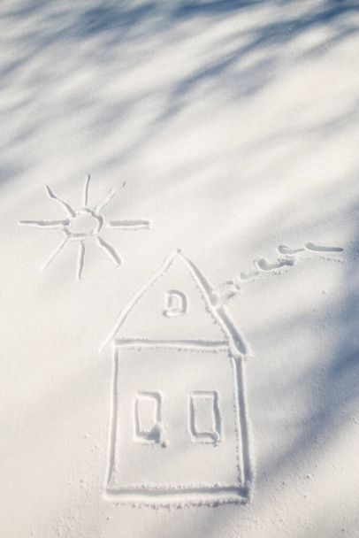 Σχέδιο στο σπίτι με καπνό από την καμινάδα και τον ήλιο στο λευκό χιόνι, παγωμένη μέρα σε εξωτερικούς χώρους. - Φωτογραφία, εικόνα