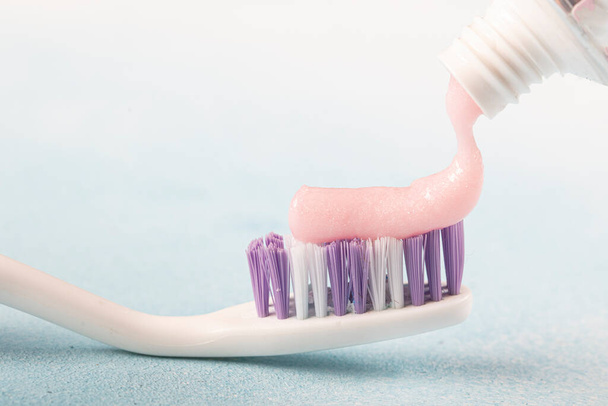 Hammasharja vaaleanpunainen hammastahna vieressä putki hammastahnaa vastaan sininen tausta  - Valokuva, kuva