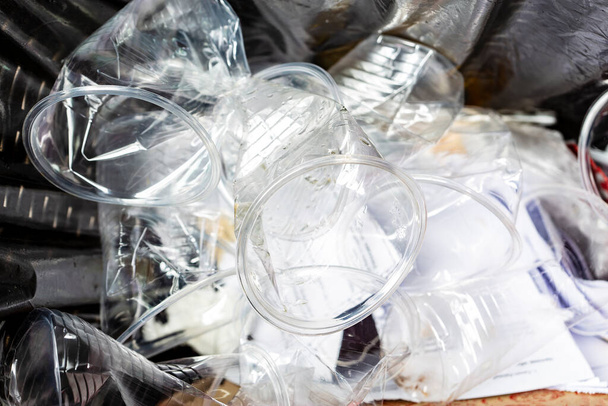 Monia muovisia kuppeja käytetään, rypistetään ja asetetaan roskakoriin juhlan jälkeen, peitetty mustalla roskapussilla. Ympäristöongelman käsite. - Valokuva, kuva
