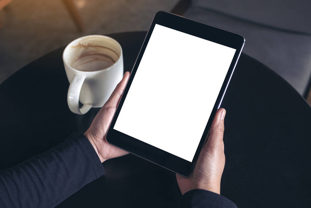 Üst görünümde siyah tableti beyaz ekran ve kahve fincanını arka planda tutan ellerin görüntüsü - Fotoğraf, Görsel