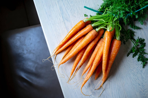 Вид сверху на пучок свежей сырой моркови лежит на столе и связан веревкой
 - Фото, изображение