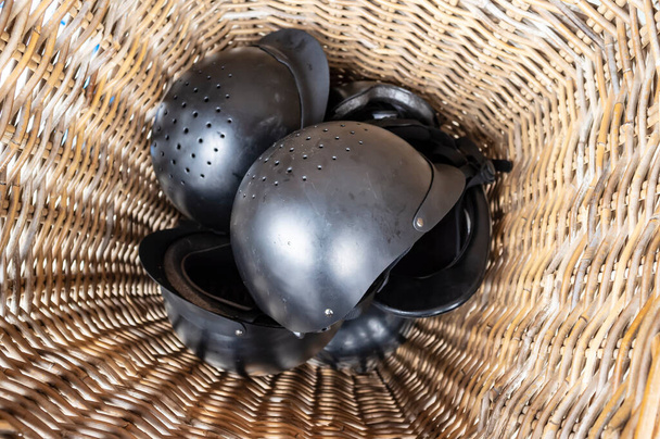 Horseback helmets lie in a pile in a rattan basket, pending use. Safety concept. Top view. - Photo, Image