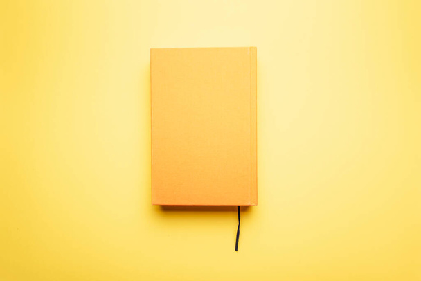 Lire à la fin de l'œuvre littéraire avec un signet se trouve sur une table lumineuse. Le livre et le fond sont jaunes. Le concept d'éducation. - Photo, image