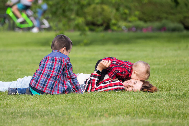 Cute wesoły dwóch chłopców brat dziecko z matką bawić się na świeżym powietrzu w parku. Szczęście i harmonia życia rodzinnego. Wspaniałe rodzinne wakacje.  - Zdjęcie, obraz